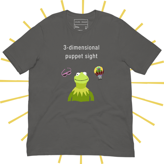 Front side of a medium grey T-shirt with plain white text reading "3-dimensional puppet sight". Below that are three shakily rendered drawings, as if done on MS Paint. The most prominent drawing in the center is Kermit the Frog from the chest up, with one of his beady eyes slightly askew. To the left of his face is a pair of the pink 3D glasses given to guests at 3-dimensional puppet sight (aka Muppet*Vision 3D). To Kermit's right is a splotchy rendering of the hot air balloon outside the attraction.