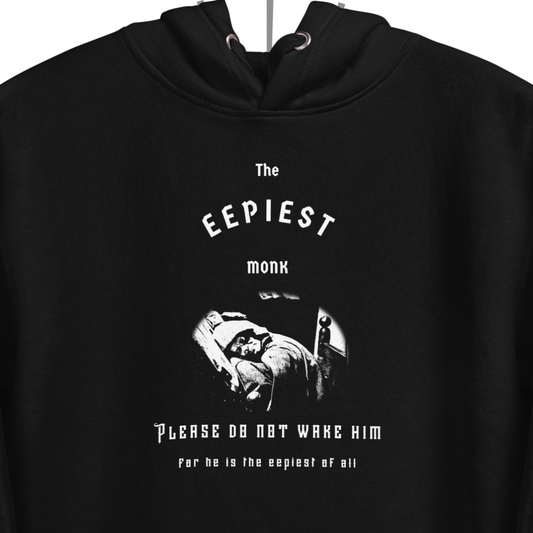 A closer look at the design on the front of the black hoodie. At the top of the design there is medieval-inspired white text reading "The Eepiest Monk". Below that is a rendering of the sleeping monk animatronic from the Spaceship Earth ride at Epcot in Disney World, all in white. Below that is more medieval-inspired text reading "Please do not wake him for he is the eepiest of all."