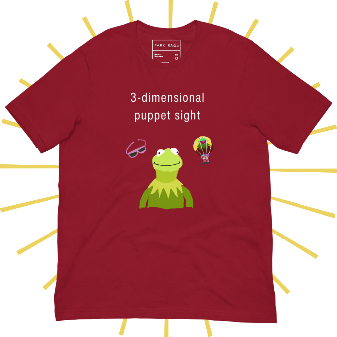 Front side of a red T-shirt with plain white text reading "3-dimensional puppet sight". Below that are three shakily rendered drawings, as if done on MS Paint. The most prominent drawing in the center is Kermit the Frog from the chest up, with one of his beady eyes slightly askew. To the left of his face is a pair of the pink 3D glasses given to guests at 3-dimensional puppet sight (aka Muppet*Vision 3D). To Kermit's right is a splotchy rendering of the hot air balloon outside the attraction.