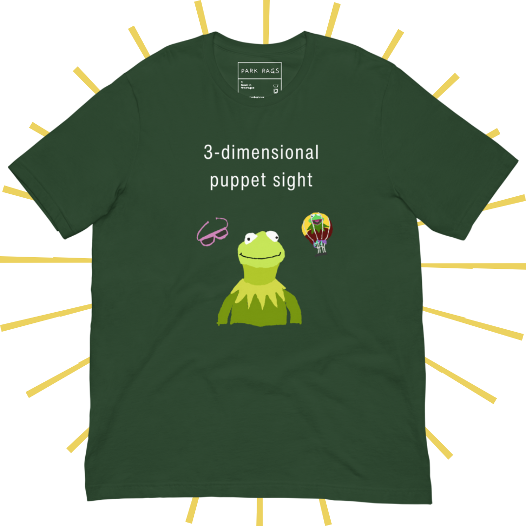 Front side of a dark green T-shirt with plain white text reading "3-dimensional puppet sight". Below that are three shakily rendered drawings, as if done on MS Paint. The most prominent drawing in the center is Kermit the Frog from the chest up, with one of his beady eyes slightly askew. To the left of his face is a pair of the pink 3D glasses given to guests at 3-dimensional puppet sight (aka Muppet*Vision 3D). To Kermit's right is a splotchy rendering of the hot air balloon outside the attraction.