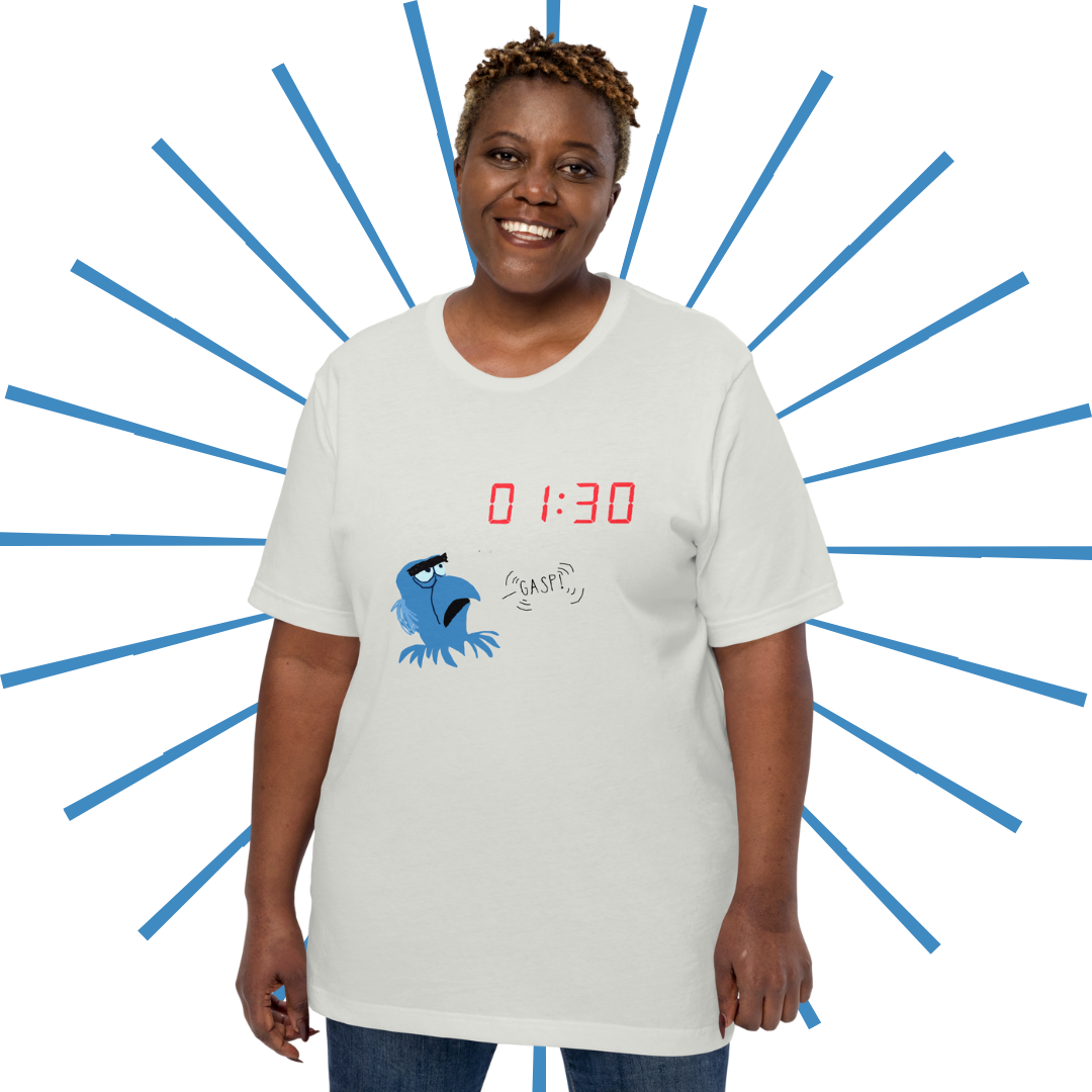 Plus-sized Black woman with short hair wearing the dusty white version of the T-shirt. She stands smiling and facing the viewer.