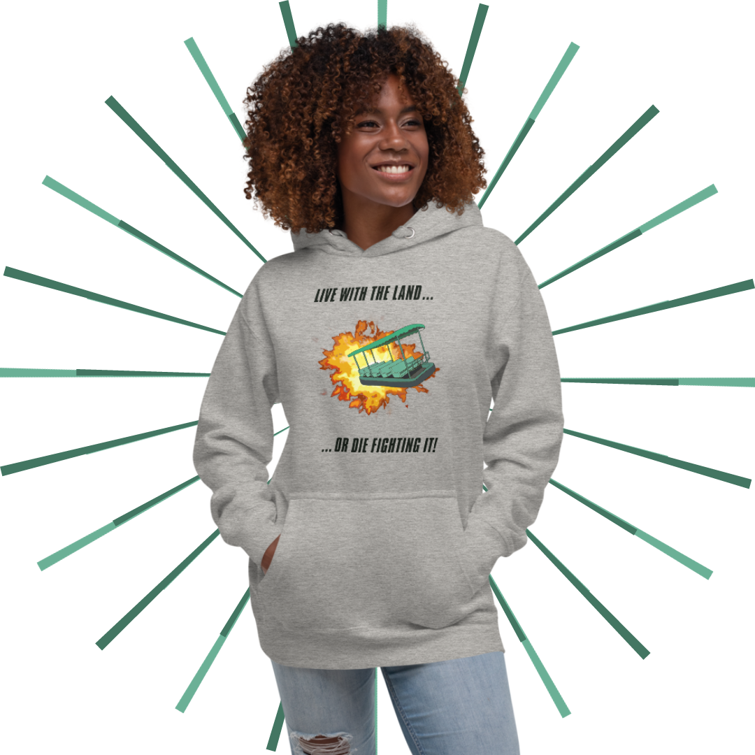 Slender Black woman with brown, curly hair wearing "Live with the Land" hoodie in grey heather with a pair of light blue, ripped jeans. She has her hands placed in the front pouch and she gazes towards her left, smiling.