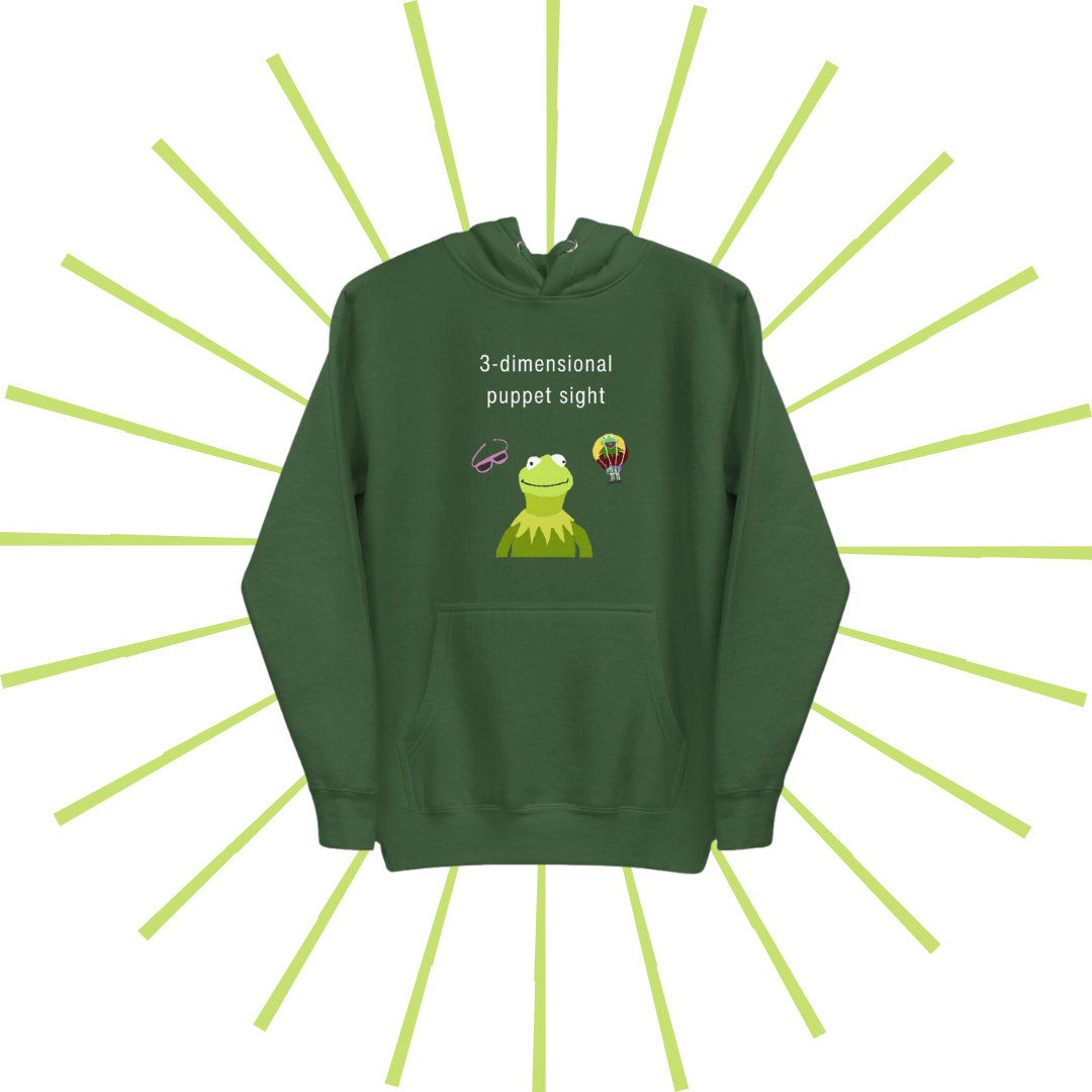 Front side of a green hoodie with plain white text reading "3-dimensional puppet sight". Below that are three shakily rendered drawings, MS Paint style. In the center is Kermit the Frog from the chest up, with one of his beady eyes slightly askew. To the left of his face is a pair of the pink 3D glasses given to guests at 3-dimensional puppet sight (aka Muppet*Vision 3D). To Kermit's right is a splotchy rendering of the hot air balloon outside the attraction. There is also a pouch towards the bottom.